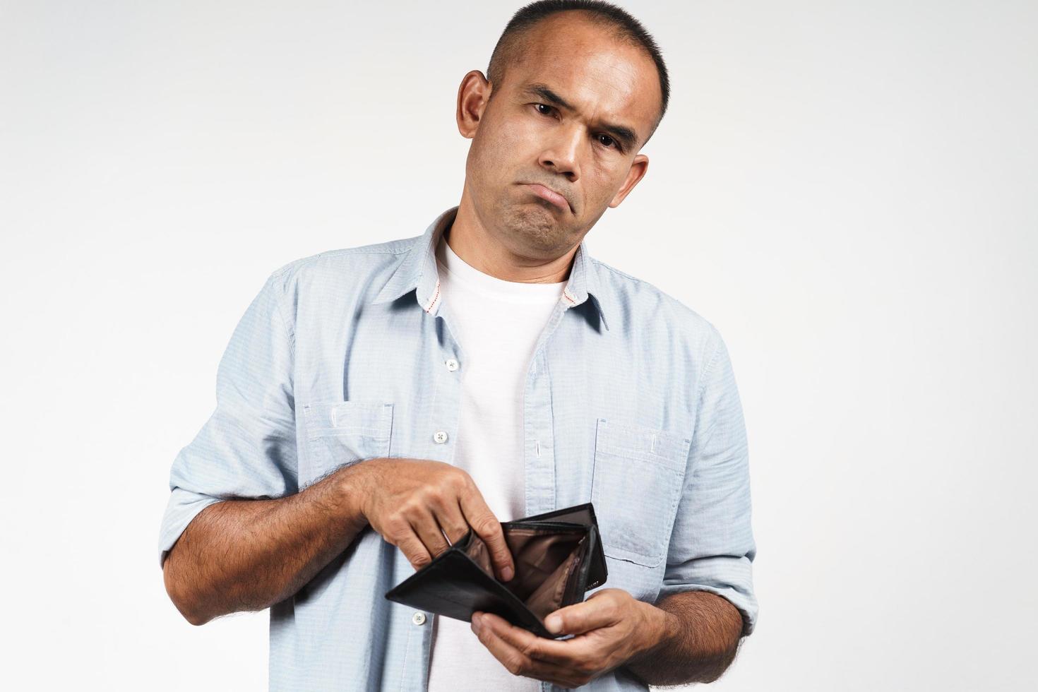 Homem preocupado segura uma carteira vazia, ilustrando a situação financeira delicada de um devedor contumaz na mira da Receita Federal.