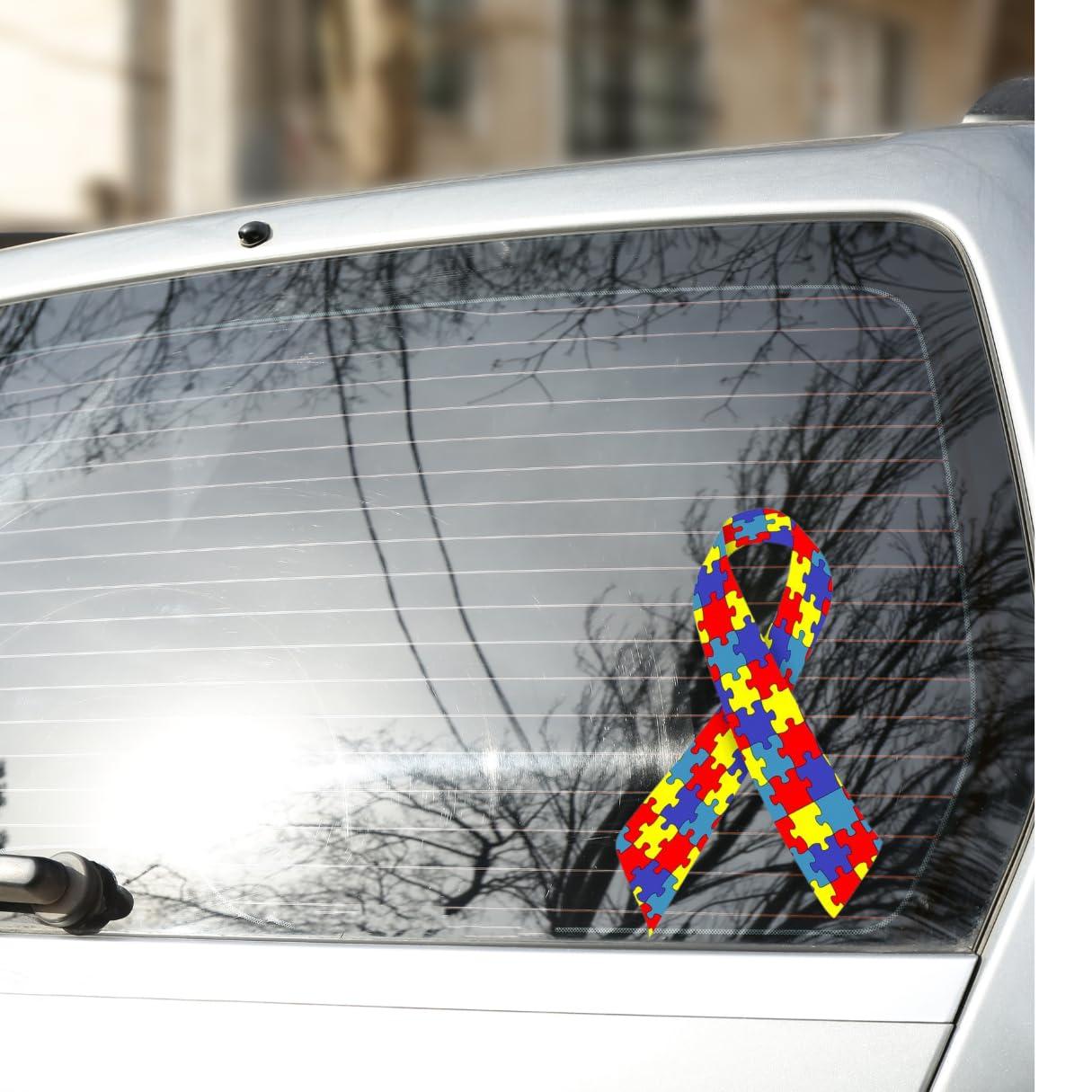 Adesivo de fita colorida com peças de quebra-cabeça, símbolo do autismo, colado no vidro traseiro de um carro, ilustrando direitos como isenção de IPVA e ICMS para PcD.