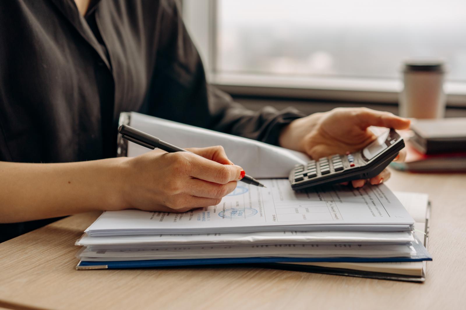 Profissional analisa documentos financeiros e usa calculadora sobre uma mesa para avaliar se a recuperação judicial vale a pena para a pequena empresa.