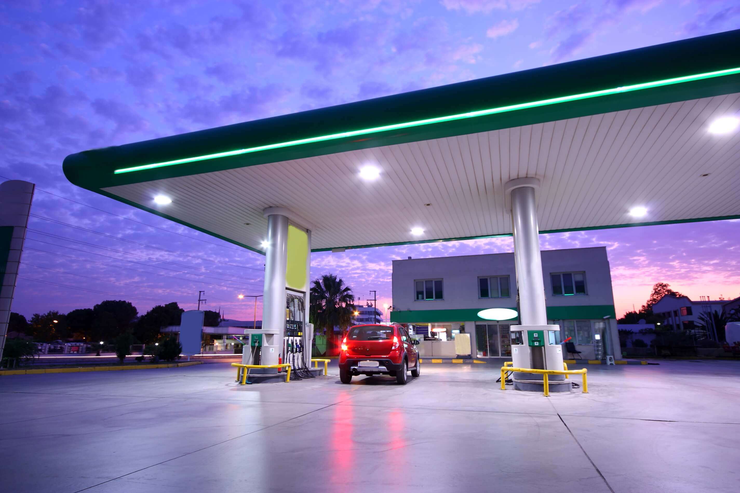Carro vermelho abastecendo em um posto de combustível ao entardecer, cenário ideal para avaliar a margem de lucro na nota fiscal.