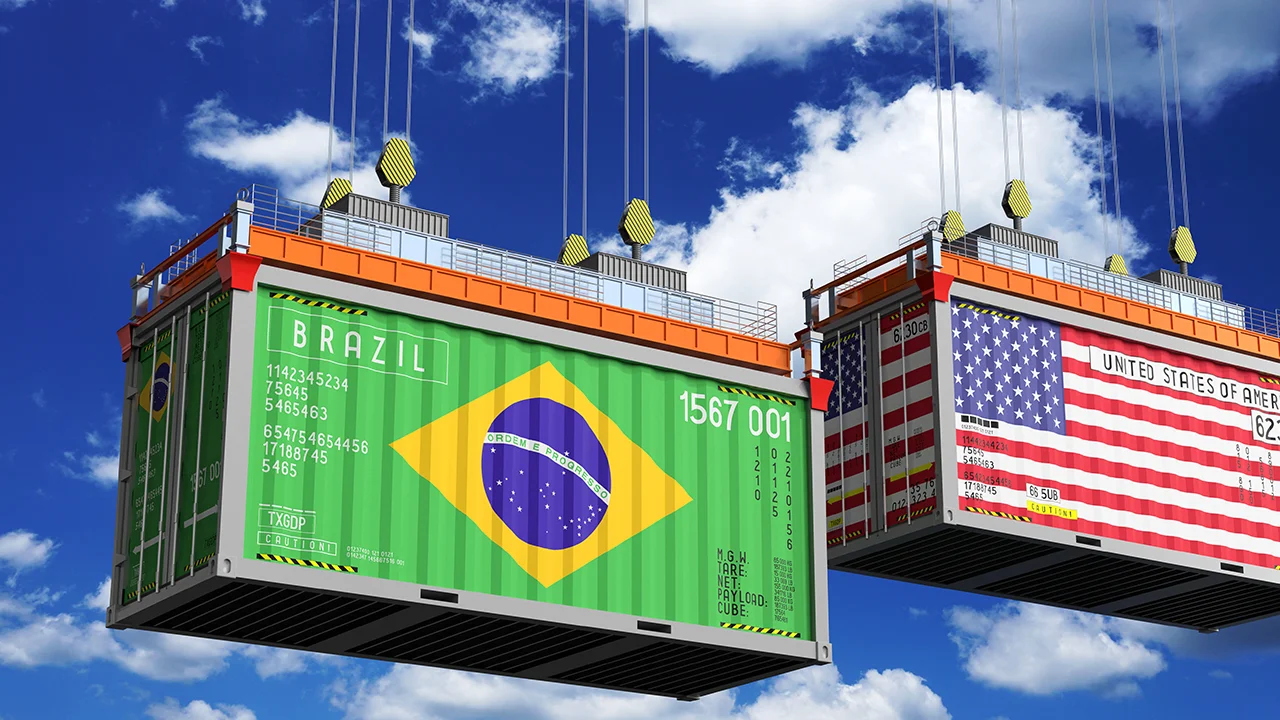 Contêineres de carga suspensos por guindastes, estampando as bandeiras do Brasil e dos Estados Unidos em um cenário de comércio exterior afetado pelo tarifaço.