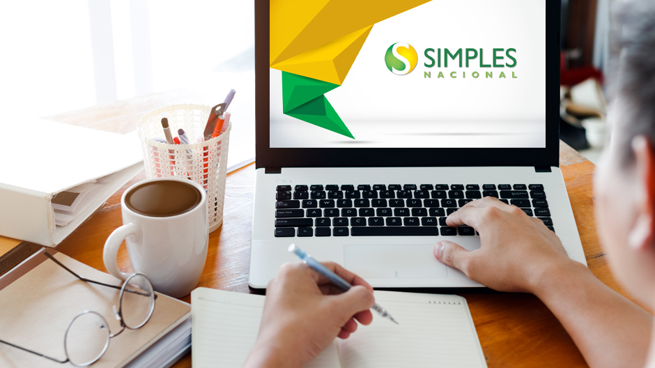 Pessoa trabalhando em um notebook com o logotipo do Simples Nacional na tela para analisar o impacto real das mudanças no regime tributário.