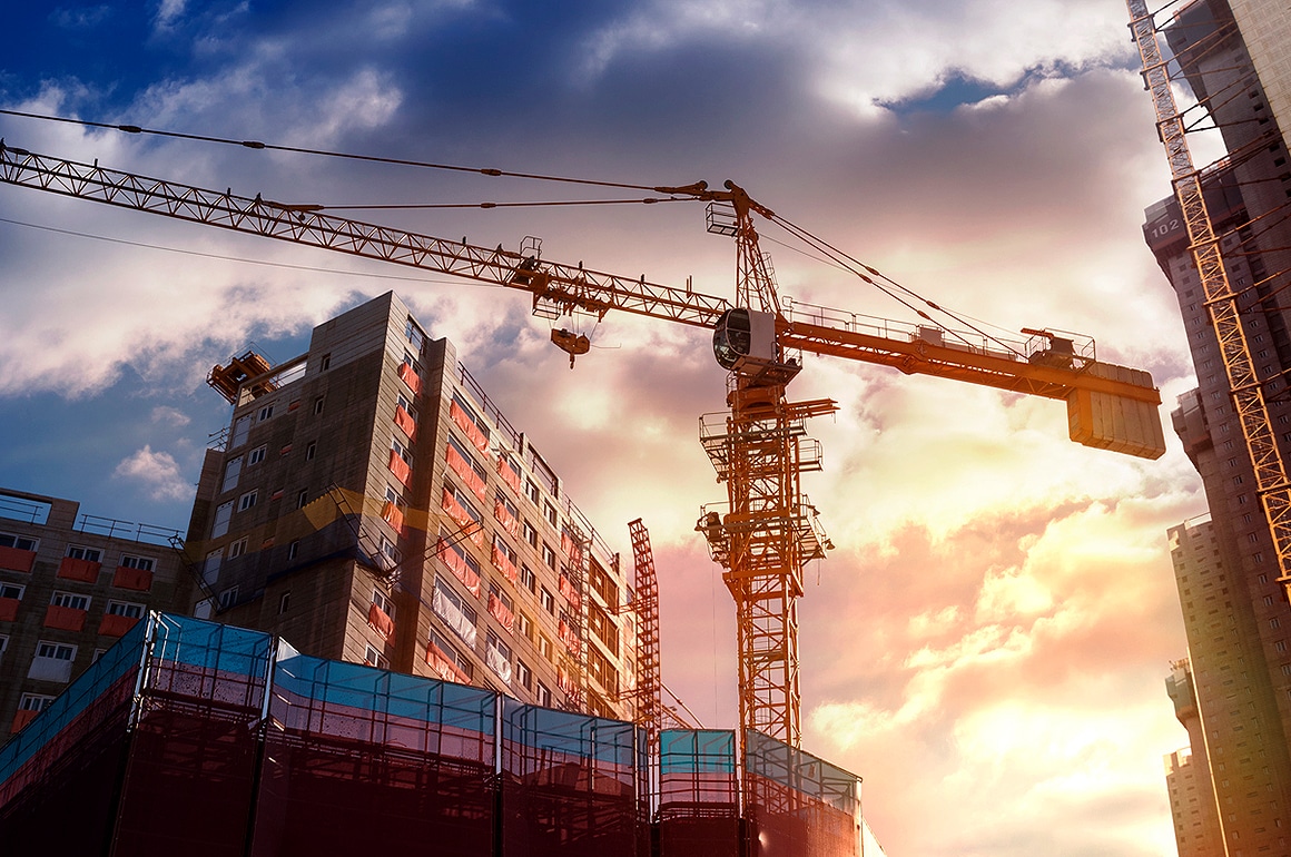 Guindaste e prédios em construção sob um céu nublado, ilustrando os impactos da Reforma Tributária na construção civil.