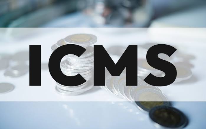 Pilha de moedas sobre a mesa com a palavra ICMS em destaque, ilustrando créditos tributários para empresas.