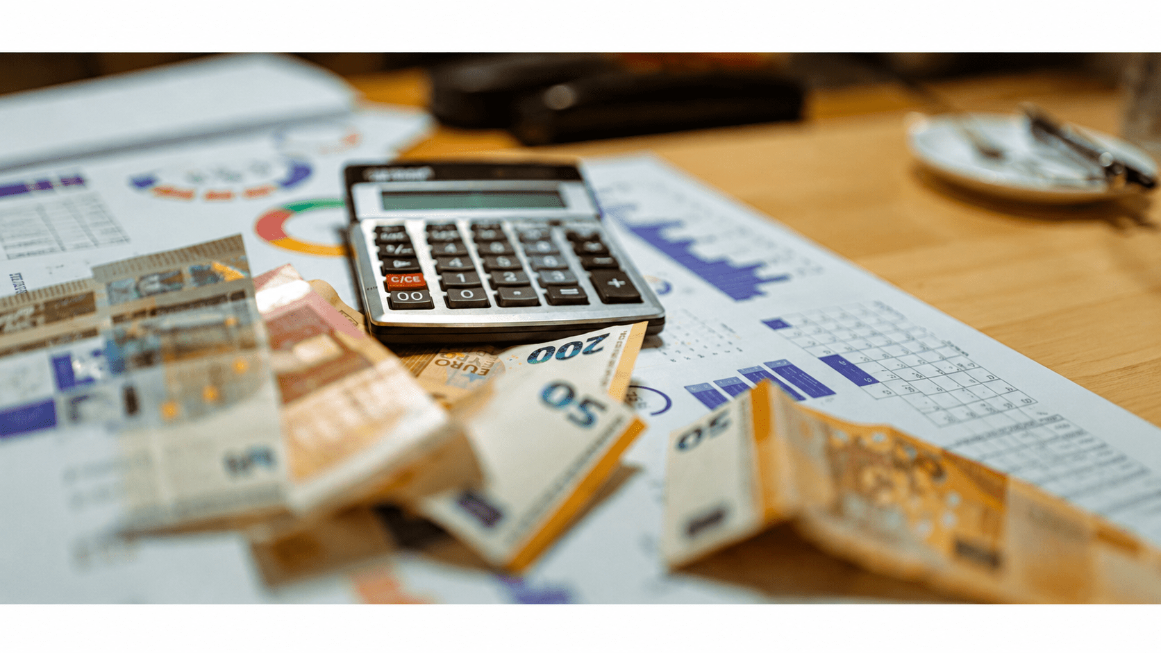 Calculadora e cédulas de dinheiro sobre documentos financeiros e gráficos, ilustrando planejamento econômico e riscos de recuperação judicial.