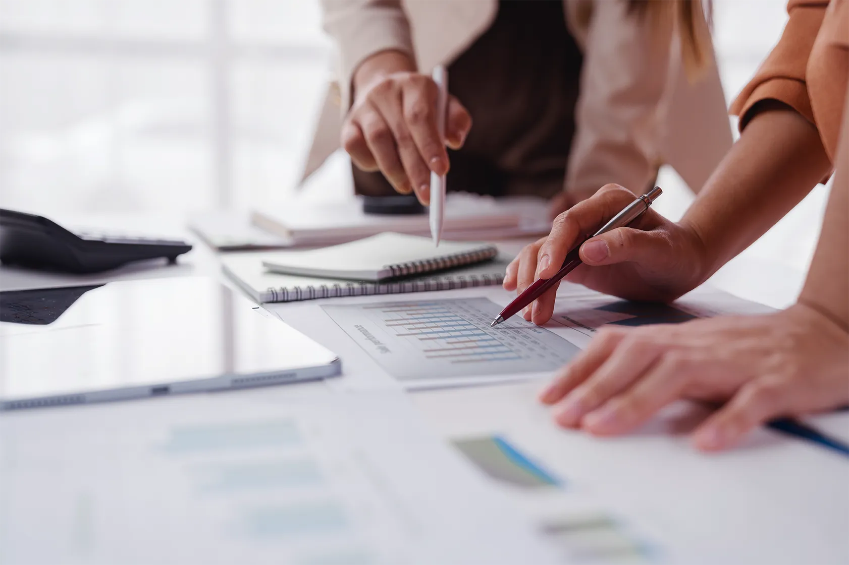 Profissionais analisam gráficos financeiros e planilhas em uma mesa de escritório para estimar a arrecadação da CBS.