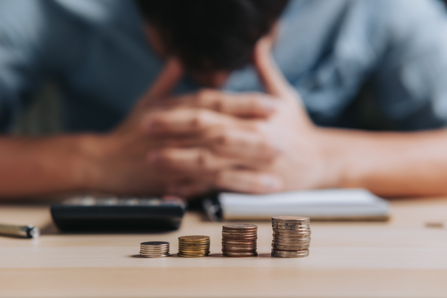 Homem de cabeça baixa com as mãos na testa, demonstrando preocupação com dívidas e inadimplência financeira.