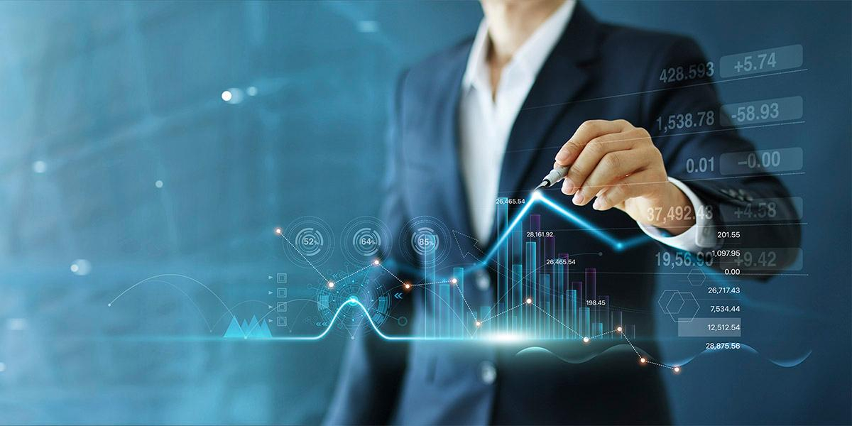 Profissional de terno aponta para gráficos financeiros digitais, ilustrando a Reforma Tributária que mexe na estratégia dos negócios.