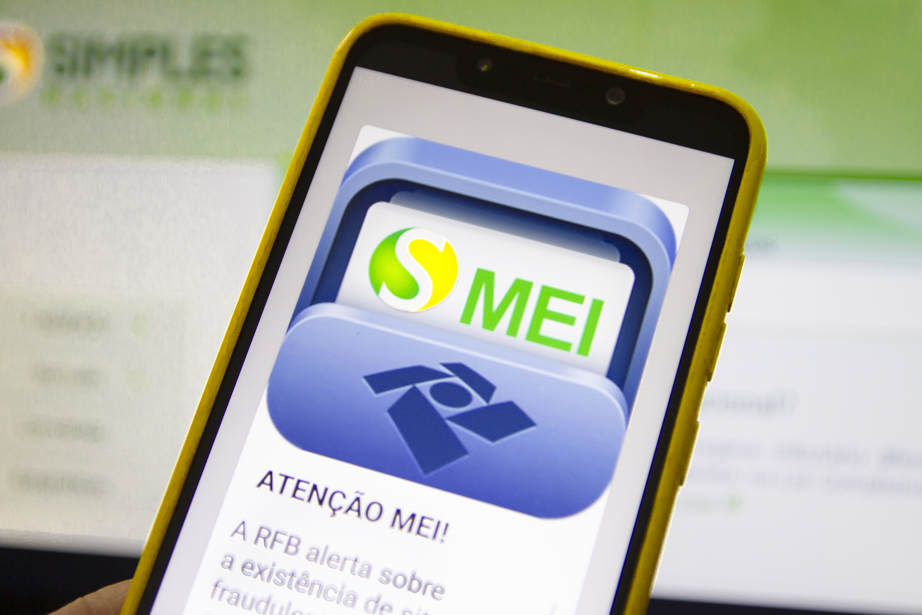 Smartphone com capa amarela exibindo na tela o aplicativo do MEI, relacionado à regularização de dívidas e Transação PGFN.