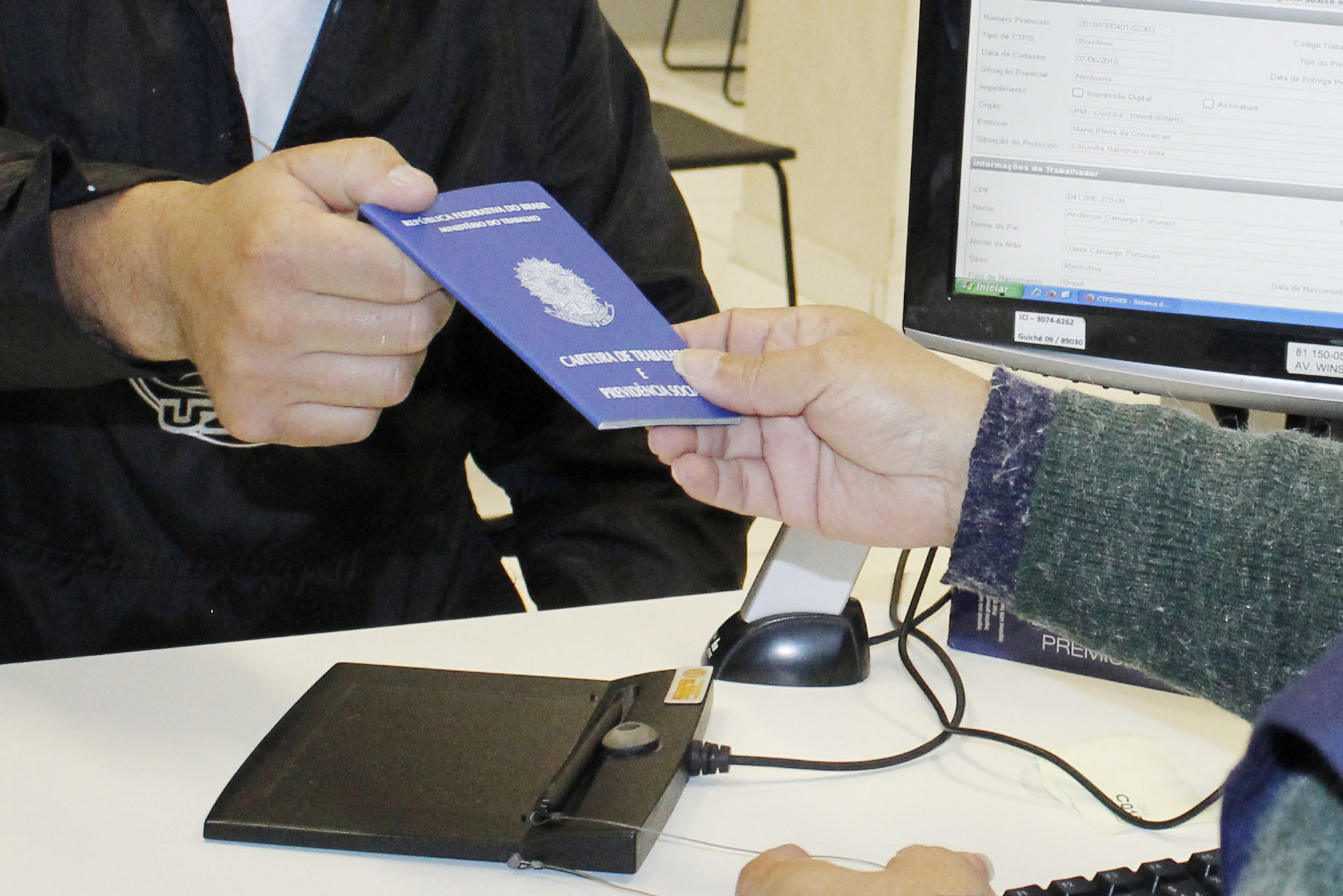 Pessoa entregando uma carteira de trabalho azul em um balcão de atendimento, representando a transição de trabalhadores CLT para MEI.