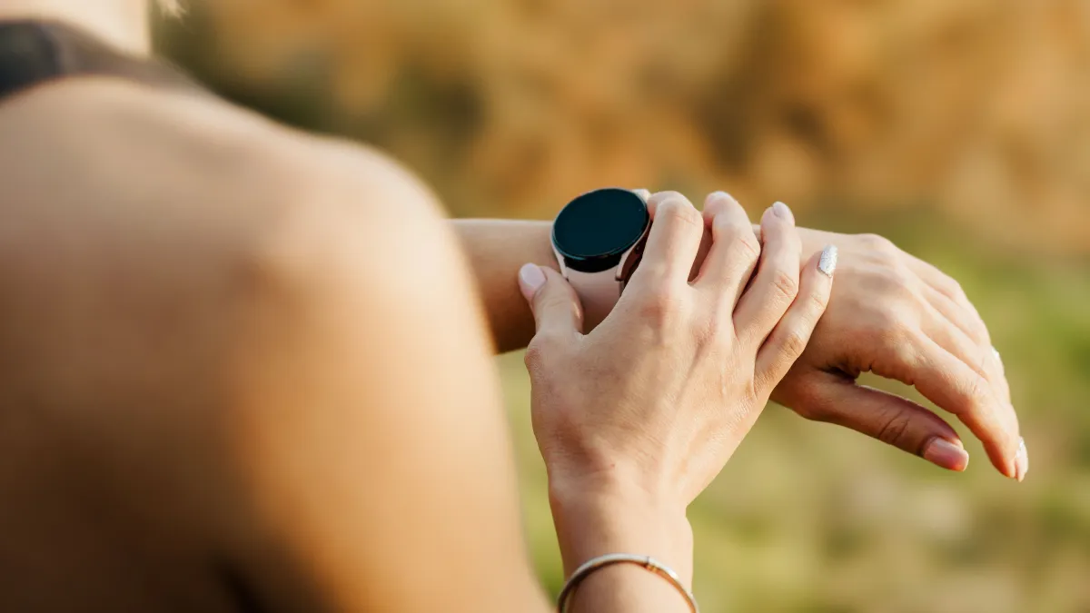Mulher olha atenta para o smartwatch no pulso, lembrando que o prazo para regularizar os débitos e salvar o CNPJ MEI está acabando.
