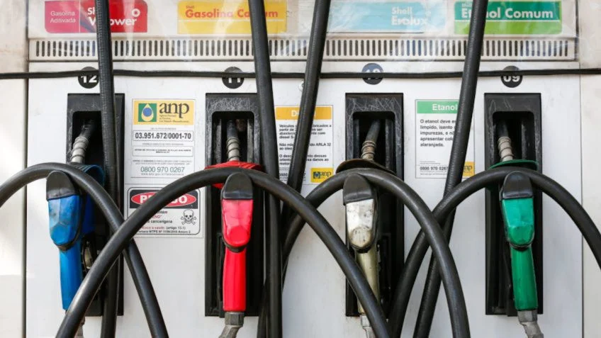 Bombas de combustível em um posto, ilustrando o impacto do preço da gasolina e dos impostos no bolso do consumidor.