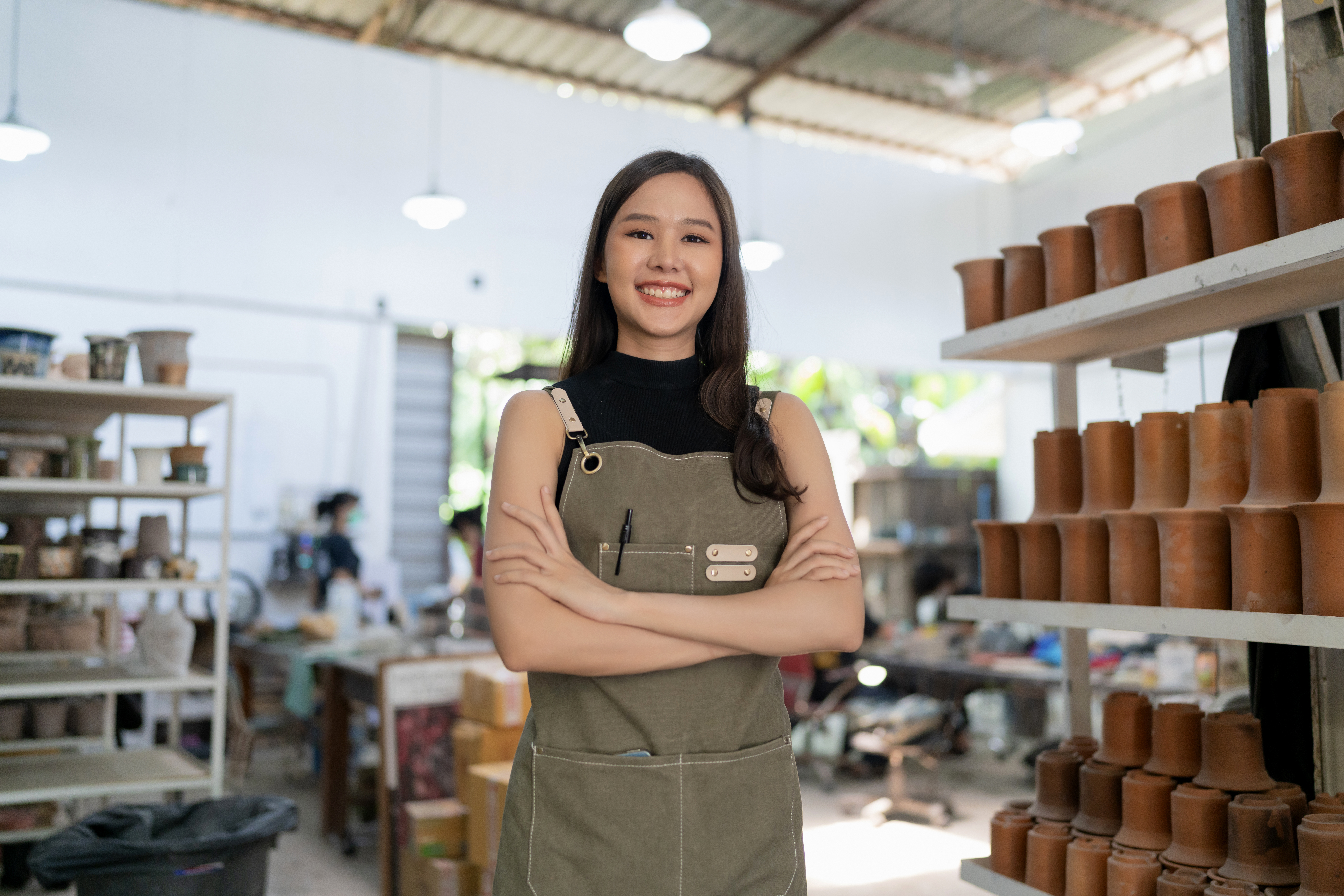 Empreendedora sorridente de avental em sua loja de cerâmica, ilustrando a escolha do tipo de empresa ideal para abrir um CNPJ.