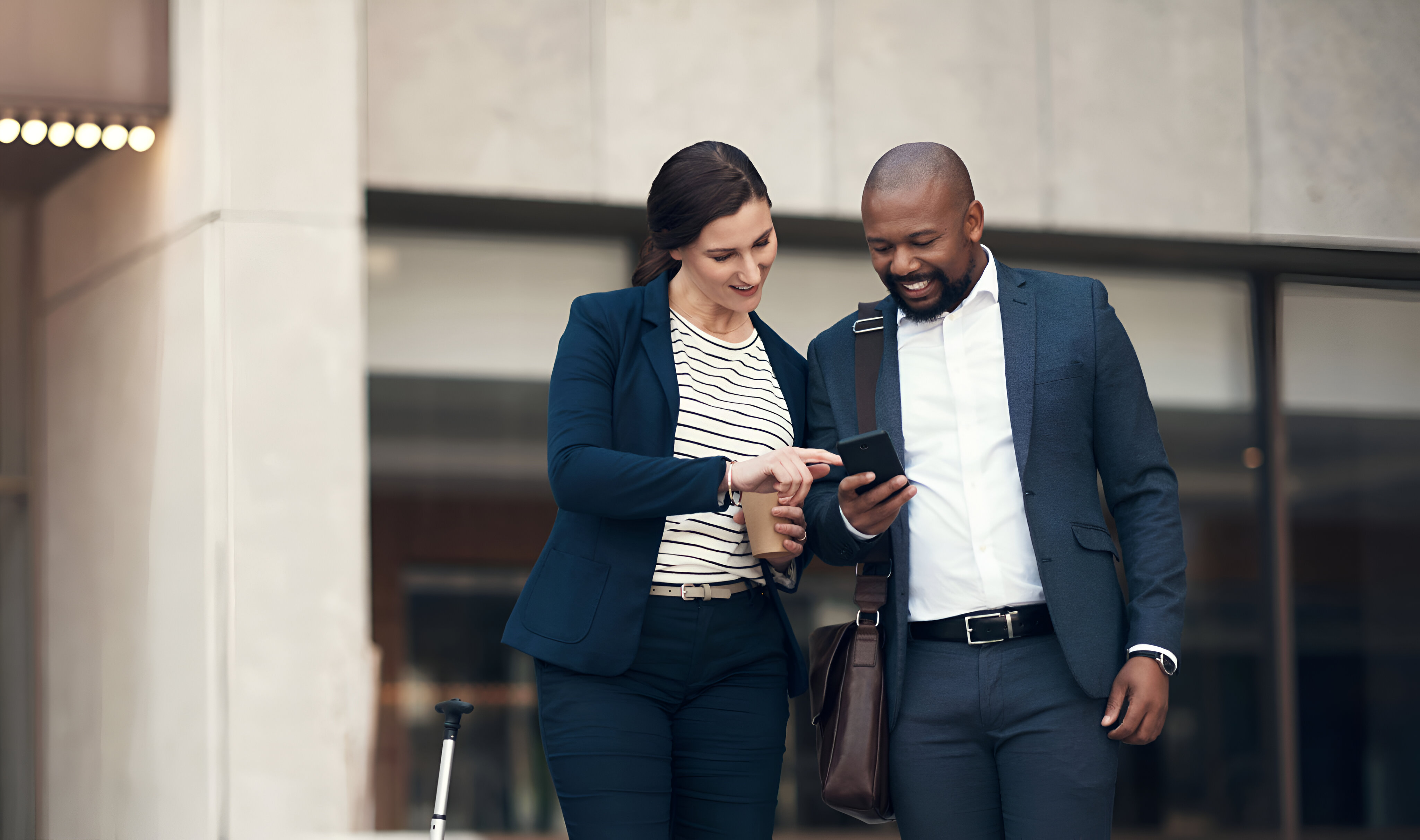 Casal de empreendedores sorrindo enquanto escolhem o tipo de empresa ideal para o CNPJ em um smartphone na rua.