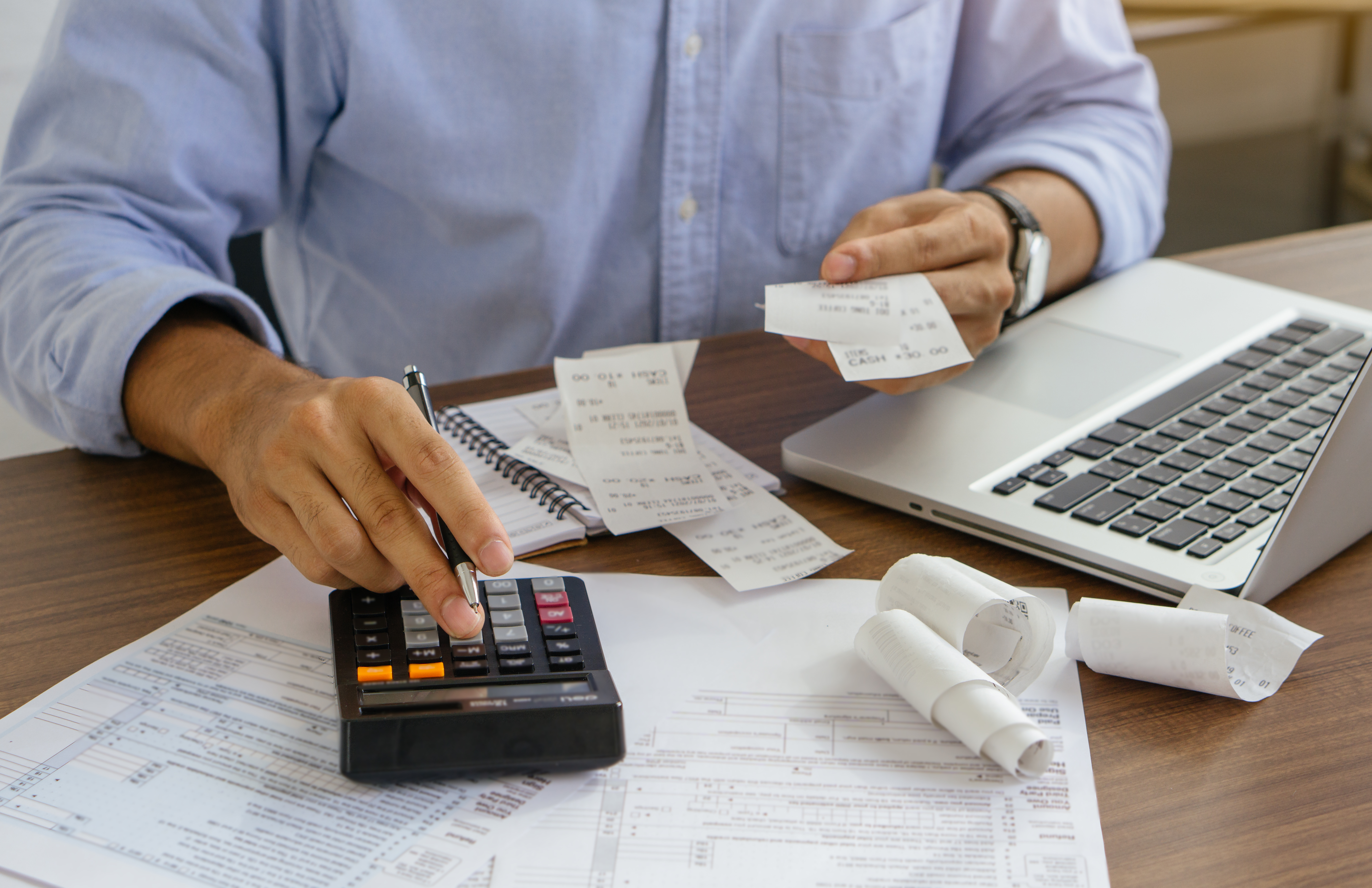 Profissional calcula impostos e notas fiscais de serviços sobre a mesa, ilustrando as novas regras que entram em vigor em outubro.